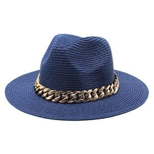 Close-up of navy blue straw fedora hat with a chunky gold chain and weaving texture
