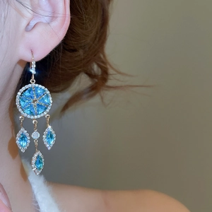 Detail view of gold drop earrings with blue crystals and sparkling cubic zirconia stones