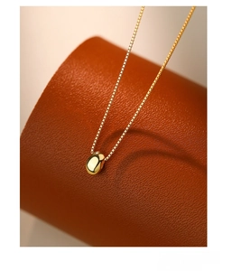 Macro shot of polished S925 silver bean pendant with sleek gold plating on leather display