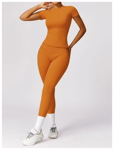Close-up of high-stretch orange yoga set featuring zip-up long sleeve top and leggings