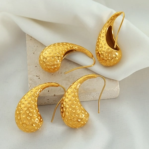 Retro 18K gold teardrop earrings with hammered texture on natural stone background