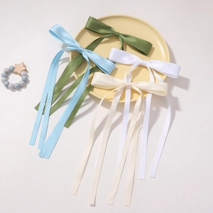Close-up of elegant satin bow hair clips in light blue, green, white, and beige colors