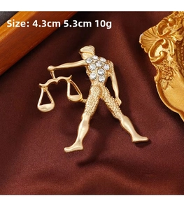 Detail of Libra zodiac brooch in gold finish with sparkling rhinestones and vintage satin background