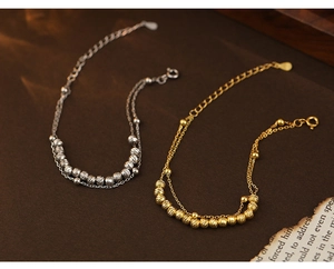 Macro detail of double-layered silver bracelets with textured beads and adjustable clasps