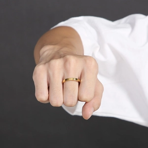 Close-up of a 3mm polished gold minimalist stainless steel ring on a model's finger