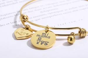 Detail of adjustable gold bracelet with heart and round charms engraved with Love mi mama