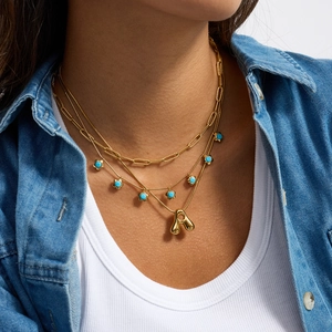 Primo piano della collana multistrato in oro con perle turchesi e grande pendente ad A