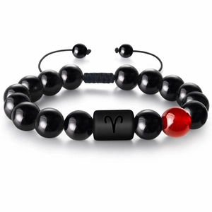 Détail macro du charme Bélier sur un bracelet en perles tissées noires et agate rouge