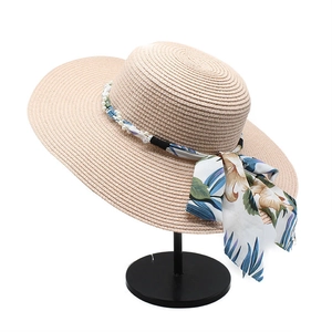 Wide brim straw sun hat with floral ribbon and pearl accents on a white background