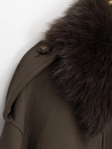 Close-up of fluffy faux fur collar and shoulder buckle strap on dark brown leather jacket