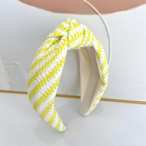 Détail d'un serre-tête en paille tressée jaune et blanc avec nœud supérieur et doublure douce