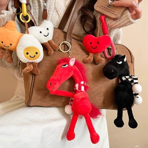 Close-up of colorful flocked horse pendant hanging on a brown leather shoulder bag