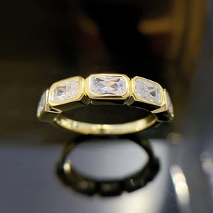 Macro shot of gold-plated ring with three rectangular zircons and mirror reflections