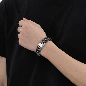 Gros plan détaillé d'un bracelet gourmette en argent porté au poignet sur fond de tissu noir