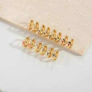 Detail of gold hoop earrings with multi-colored enamel cross charms on stone base