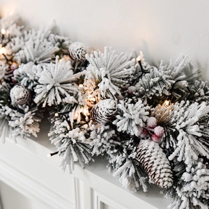 Guirlande de Noël enneigée avec pommes de pin, baies rouges et lumières LED chaleureuses