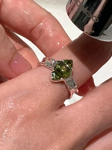Macro shot of olive green gemstone ring with silver irregular texture under water