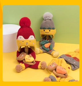 Close-up of children's knitted beanie and scarf set featuring cute cartoon bears and pom-poms