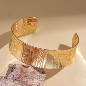 Détail du bracelet ouvert doré géométrique avec rayures verticales et textures perlées