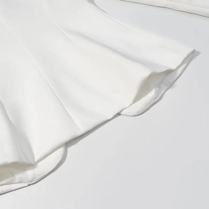 Détail de l'ensemble blanc à col en V montrant la texture du tissu et l'ourlet lisse