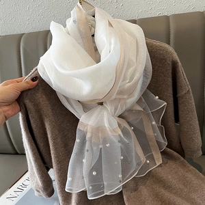 Detail of white translucent silk scarf with elegant pearl beads and champagne trim