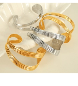 Detail of layered textured gold and silver metal bangles on a white shell prop