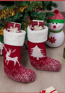 Details von roten gestrickten Weihnachtssocken mit Rentier- und Baummuster auf Holzboden