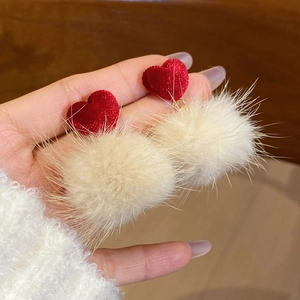 Détail de boucles d'oreilles cœur rouge et pompon blanc duveteux pour la saison d'hiver