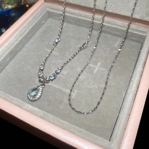Macro view of teardrop blue gemstone pendant necklace with shimmering silver chain details