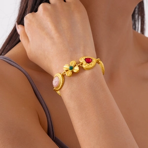 Vintage gold charm bracelet with pink cameo floral and red heart pendants on a model