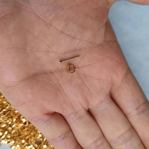 Close-up of a gold-plated earring post and butterfly back held in hand for size reference