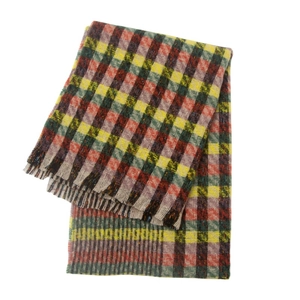 Detail view of multicolored plaid scarf with yellow and red patterns and fringe edges