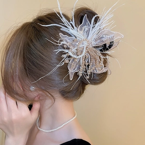 Detail of elegant hair claw clip with white feathers, lace flowers and pearls