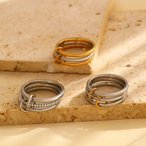 Close-up of stacked gold and silver stainless steel rings with diamonds on stone