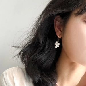 Close-up of elegant silver clustered freshwater pearl earrings worn by a model