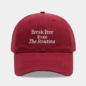 Close-up of burgundy cotton baseball cap with white Break Free From The Routine embroidery