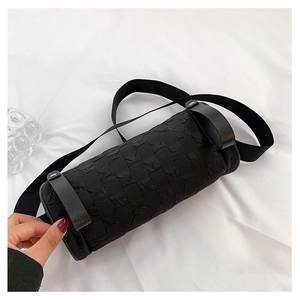 Detail of black cylindrical crossbody bag featuring textured seersucker fabric and wide strap