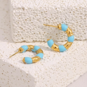 Detail of gold-plated stainless steel C-shape earrings with turquoise enamel on white stone