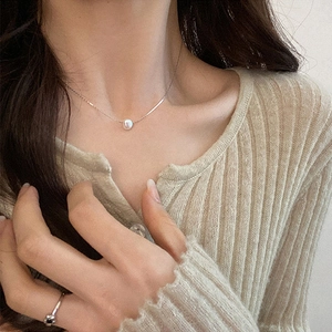 Close-up of minimalist silver necklace with a single pearl pendant worn by a model
