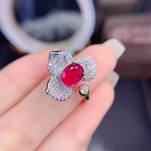 Close-up of a floral silver ring with red oval gemstone and pavé set micro diamonds