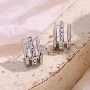 Macro shot of silver J-shaped triple-row earrings with sparkling pavé rhinestones