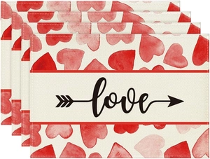 Detailed view of linen placemats set featuring watercolor red hearts and love text