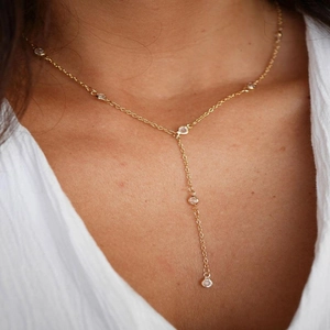 Macro shot of gold Y-shaped necklace with round zircon accents on model's neck