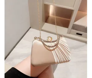 Detail of champagne satin evening bag with pleated design, pearls, and crystals on top frame