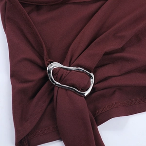 Detail of burgundy knit fabric tied with an irregular silver metal ring fastener