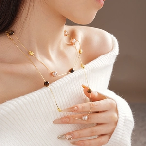 Close-up of double-layer necklace with brown tiger eye beads and pearls on white sweater
