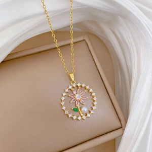 Detail of flower pendant necklace featuring pink gems and pearl on gold chain