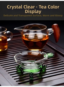 Macro shot of glass tea infuser with green base and wood-handle pitcher on tray