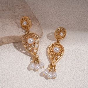 Detail view of gold vintage hollow flower earrings with imitation pearls and tassels
