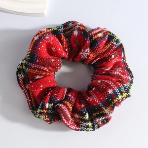 Detail of red plaid Christmas scrunchie with white snowflake patterns and soft knit texture